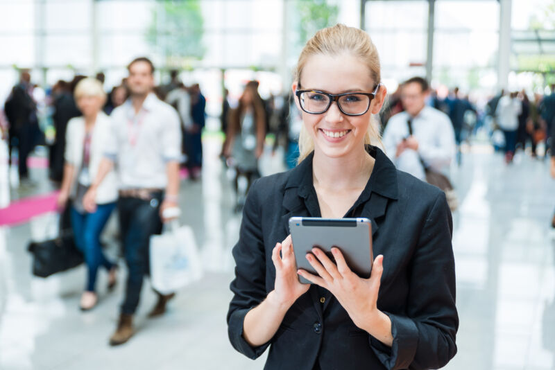 woman with glasses and tablet smiling at school work or career fair job hunting