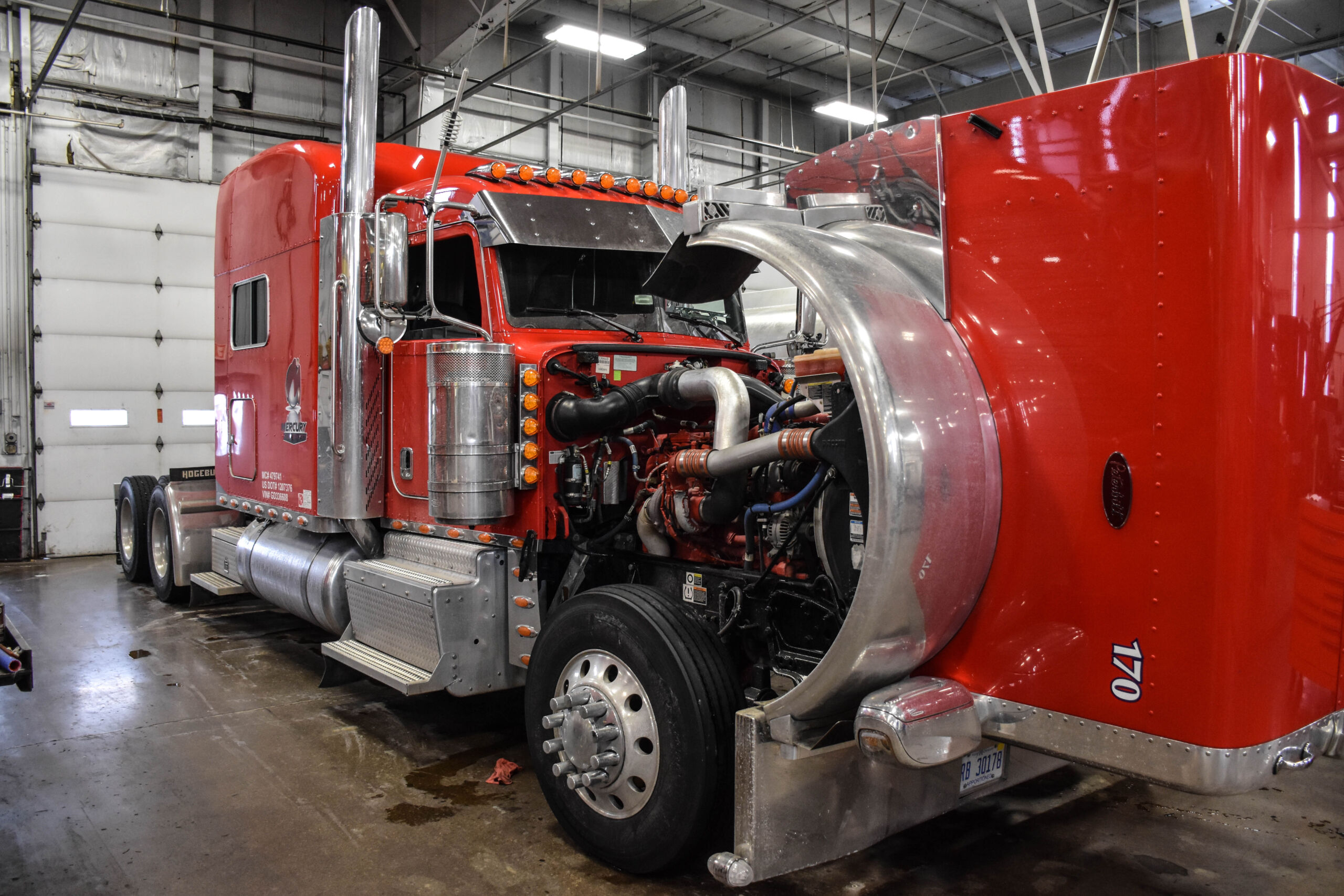 Red Peterbilt truck with open hood in service bay for maintenance to prepare for Cold Weather