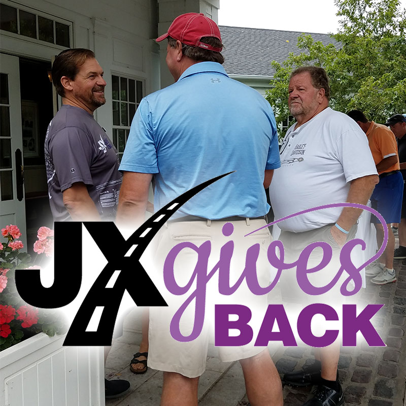 JX Gives Back logo over photo of people at golfing event