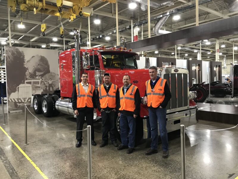 Corey and Kurt Moeggenborg pose in front of Red peterbilt ruck with their tour guide