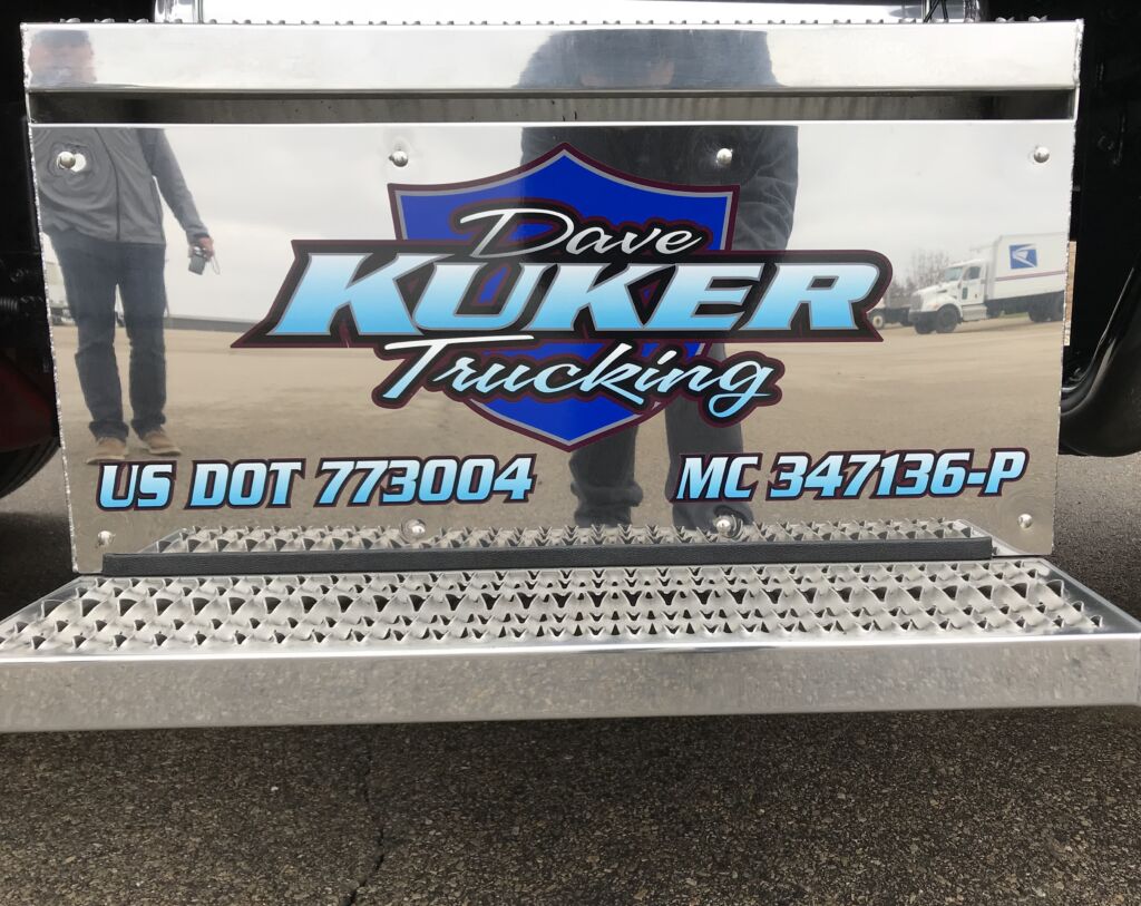 text reading dave kuker trucking over a shield with phone number underneath truck graphic