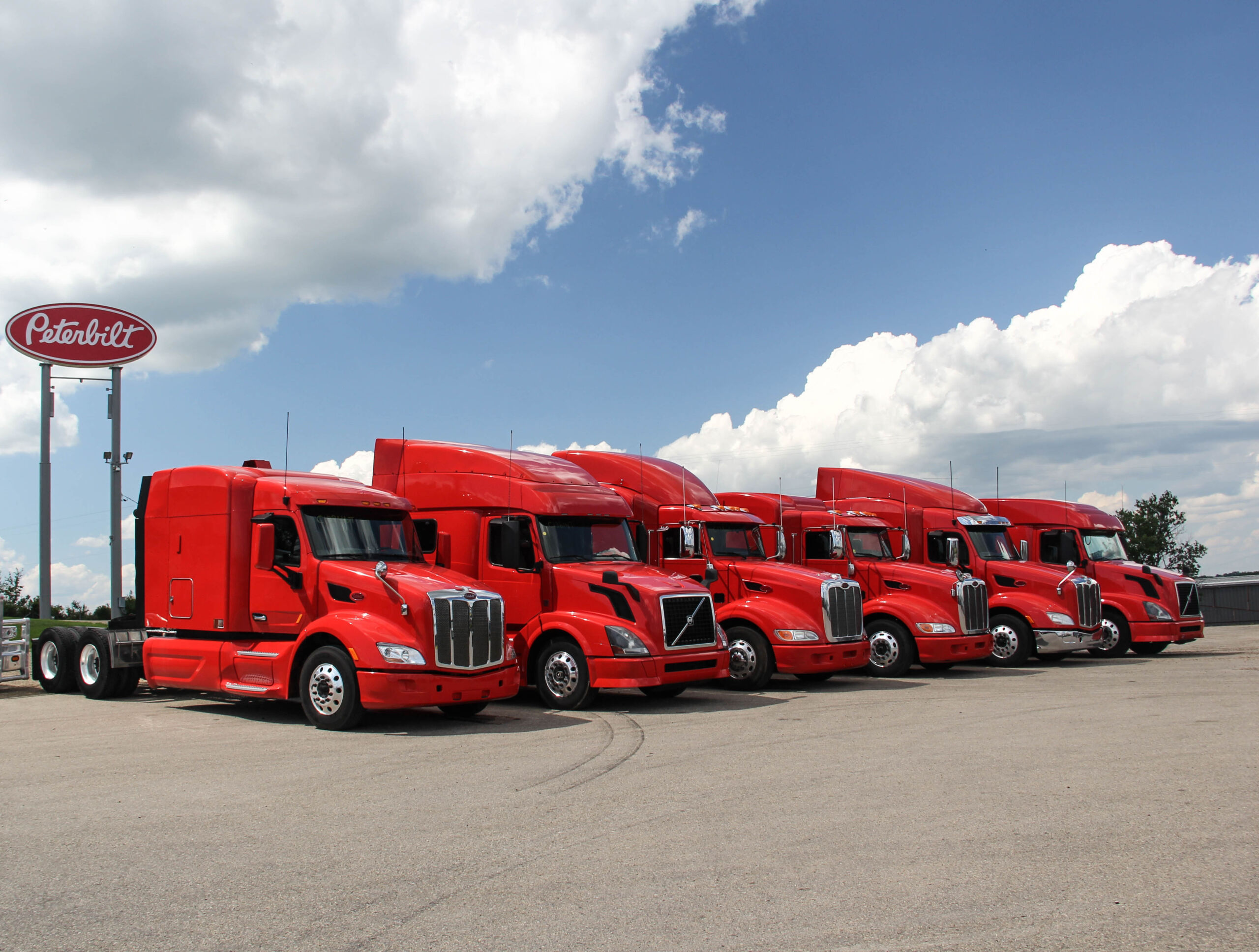 Row of red peterbilt and volvo trucks lined up for the Must-know Trucking Industry Statistics blog