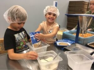 JX gives back influenced Julien age 7 and Noelle age 5 to volunteer at Feed Our Starving Children charity