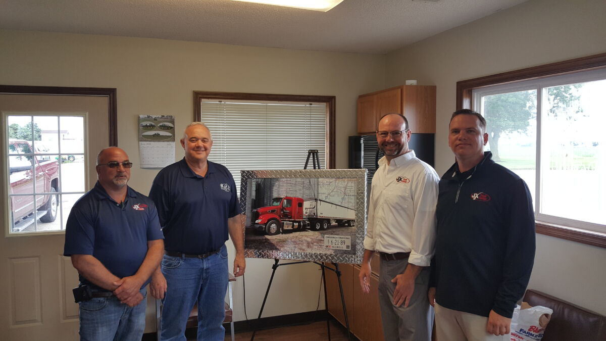Gingerich Trucking representatives posing with custom artwork from JX