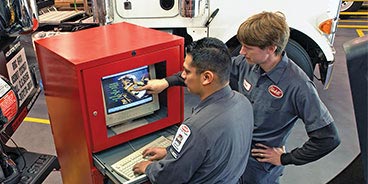 two peterbilt mechanics examine body shop computer